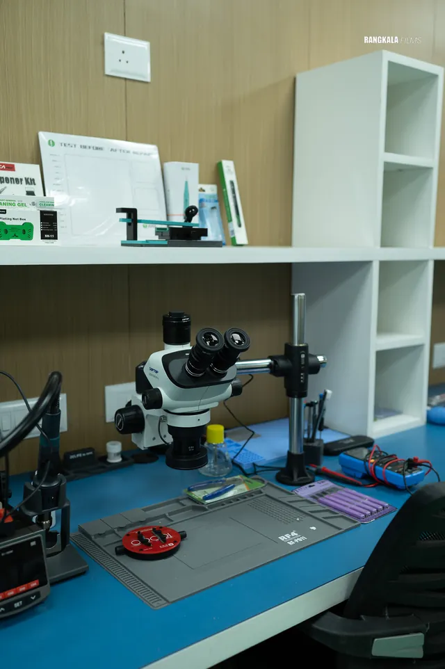 A technician bench at the Nashik workshop: stereo microscope, repair mat and multimeter